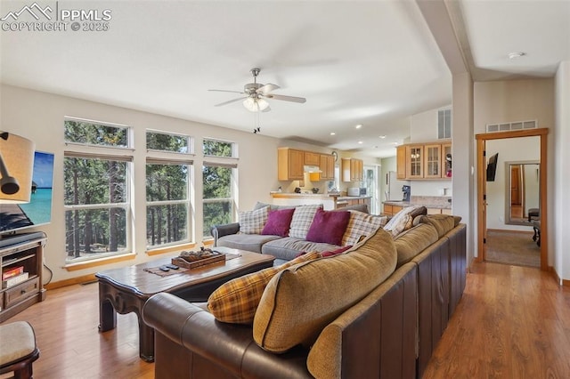 living room with light wood-style floors, baseboards, ceiling fan, and visible vents