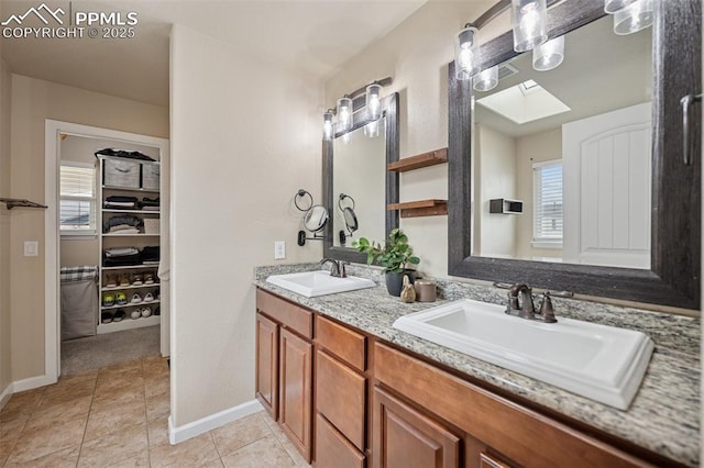 full bath featuring double vanity, baseboards, a sink, and tile patterned flooring