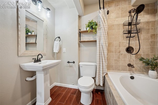 bathroom with baseboards, tiled shower / bath, toilet, and wood finished floors