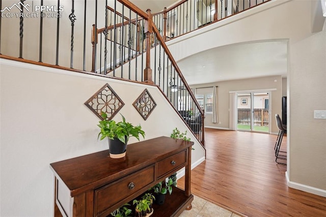 stairs featuring baseboards, arched walkways, and wood finished floors