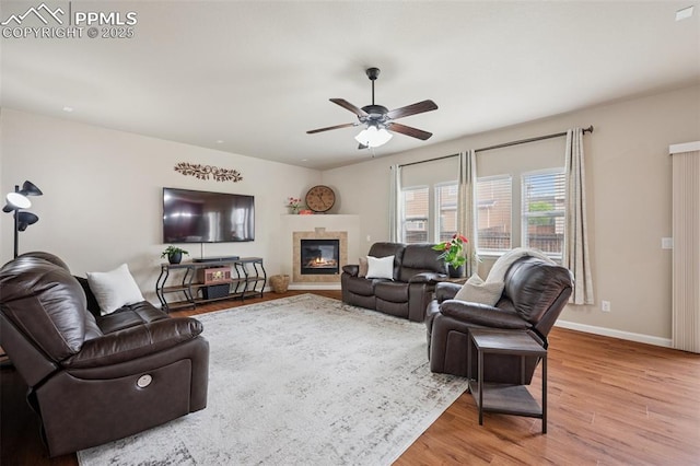 living room with baseboards, a ceiling fan, wood finished floors, and a fireplace