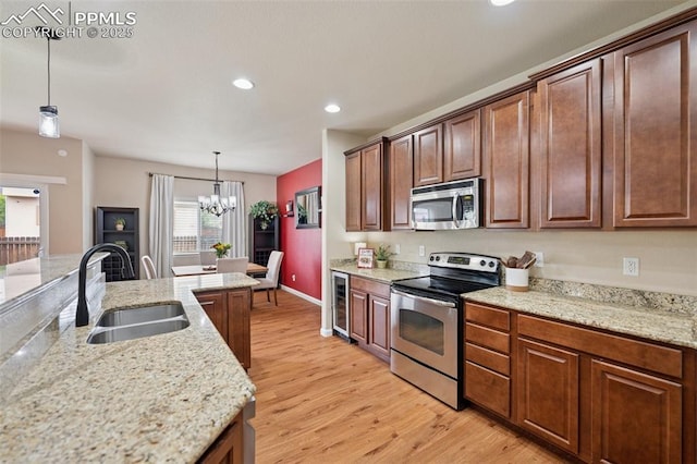 kitchen with appliances with stainless steel finishes, light wood-type flooring, a sink, beverage cooler, and a notable chandelier