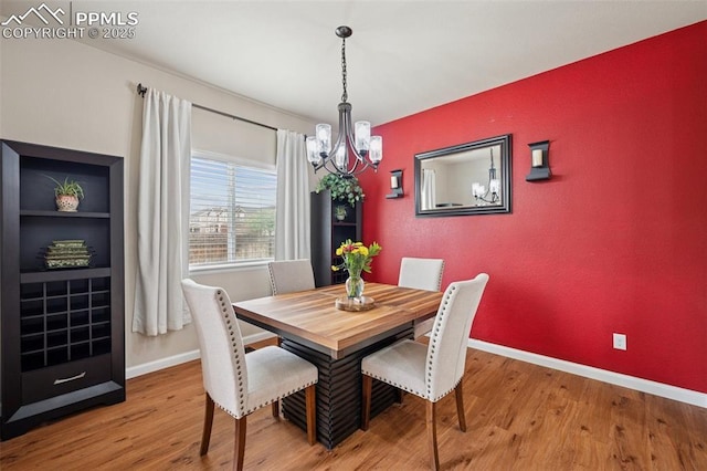 dining space featuring baseboards, wood finished floors, and a notable chandelier