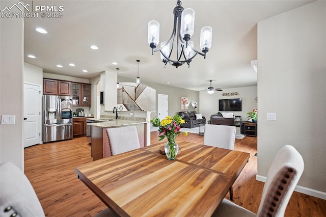 dining area featuring stairs, baseboards, ceiling fan with notable chandelier, light wood finished floors, and recessed lighting
