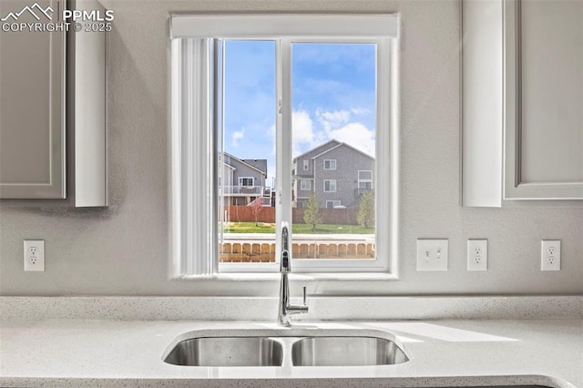 kitchen with a sink, light stone counters, and a wealth of natural light