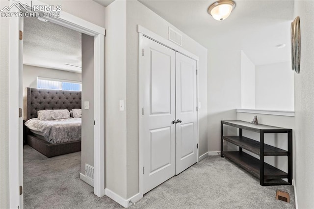 hallway featuring visible vents, carpet flooring, and baseboards