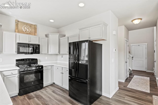 kitchen featuring light countertops, white cabinetry, black appliances, and light wood-type flooring