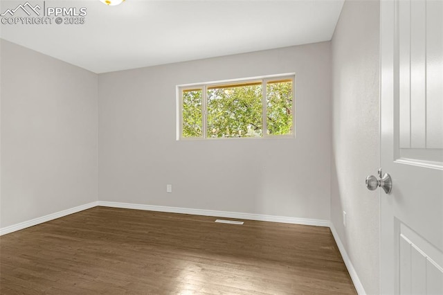 empty room with baseboards, visible vents, and wood finished floors