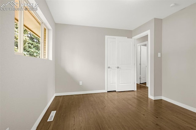 empty room with baseboards, wood finished floors, and visible vents