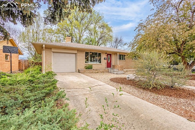 single story home with fence, an attached garage, brick siding, a chimney, and concrete driveway
