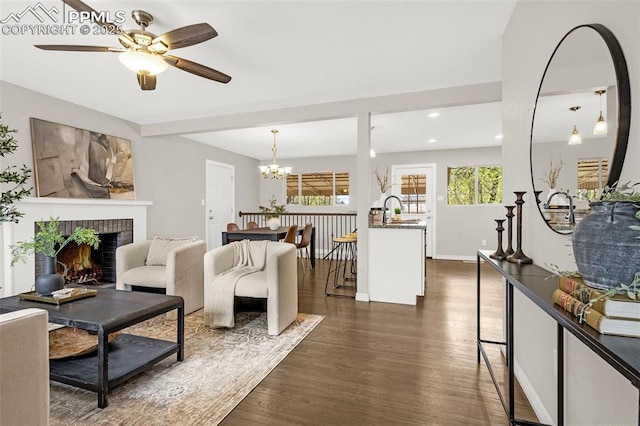 living room featuring a fireplace, dark wood finished floors, baseboards, ceiling fan with notable chandelier, and recessed lighting