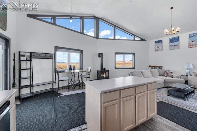 kitchen featuring decorative light fixtures, a wood stove, light countertops, open floor plan, and an inviting chandelier