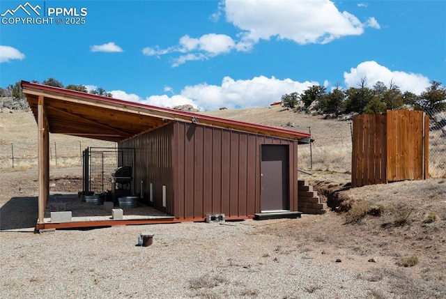 view of outbuilding with fence and an outbuilding