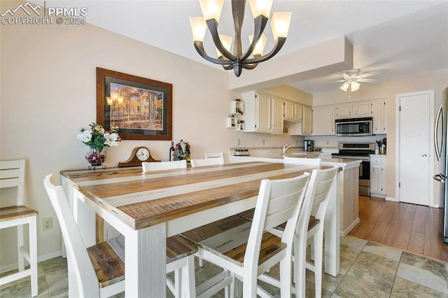dining room with baseboards and ceiling fan with notable chandelier