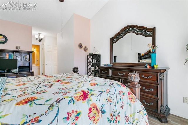 bedroom with baseboards, wood finished floors, and vaulted ceiling