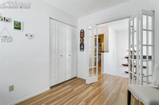 interior space with light wood-style floors, a textured ceiling, and baseboards