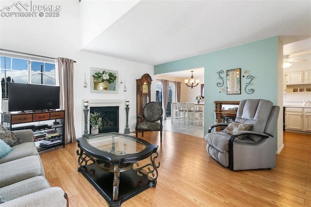 living area with a notable chandelier, a glass covered fireplace, and light wood-style flooring