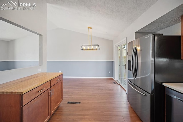 kitchen featuring appliances with stainless steel finishes, vaulted ceiling, wood finished floors, and a chandelier