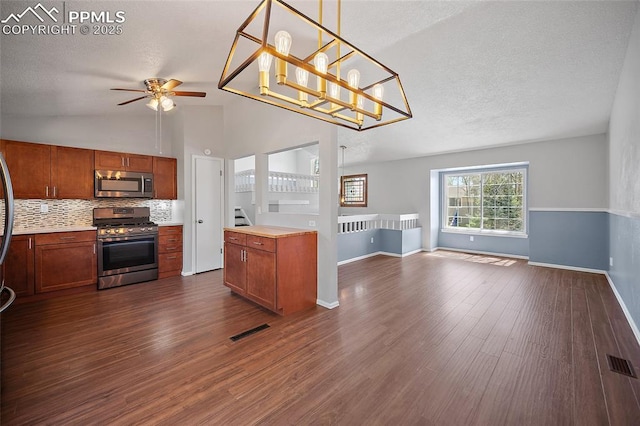 kitchen featuring ceiling fan, stainless steel appliances, open floor plan, vaulted ceiling, and visible vents