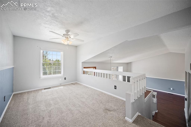 carpeted spare room featuring a textured ceiling, ceiling fan, visible vents, and baseboards