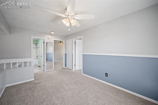 unfurnished bedroom featuring a walk in closet, ceiling fan, baseboards, carpet floors, and a closet
