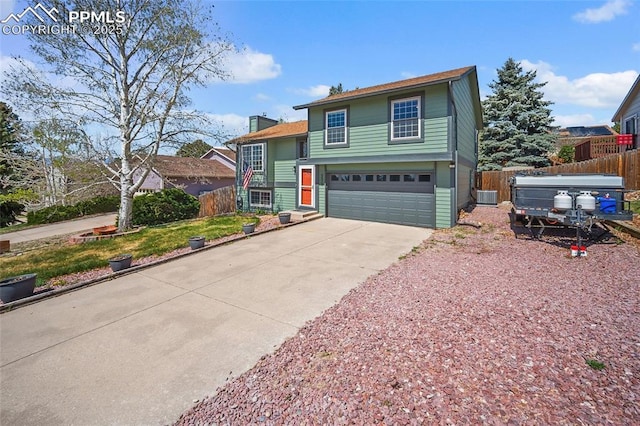 view of front of house with fence, a garage, a chimney, cooling unit, and driveway