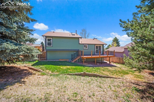 back of property with a lawn, a wooden deck, stairway, and fence