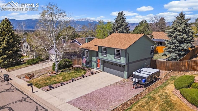 view of front facade featuring fence, roof with shingles, an attached garage, a mountain view, and concrete driveway