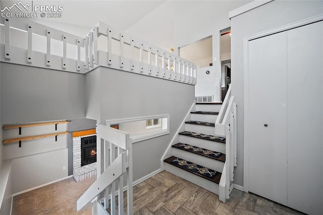 stairway with baseboards, a brick fireplace, and visible vents