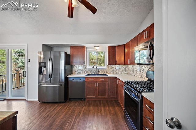 kitchen featuring a sink, dark wood-style floors, a textured ceiling, a ceiling fan, and appliances with stainless steel finishes