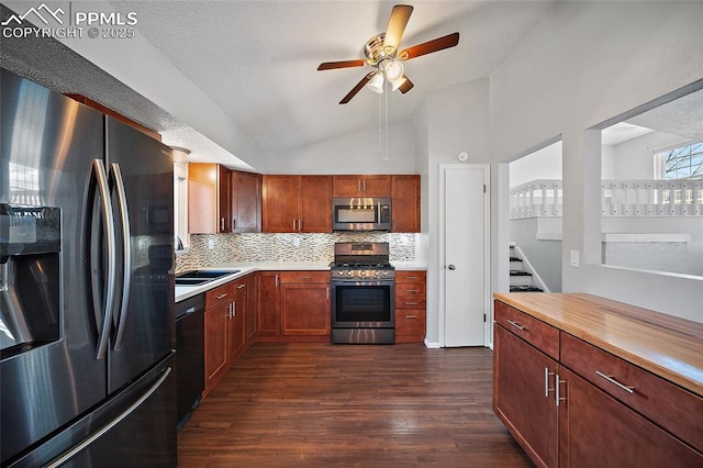 kitchen with ceiling fan, a sink, backsplash, vaulted ceiling, and stainless steel appliances