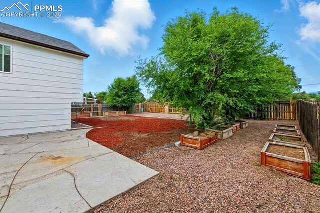 2032 Woodsong Way, Fountain, CO 80817 - fenced backyard featuring a vegetable garden and a patio