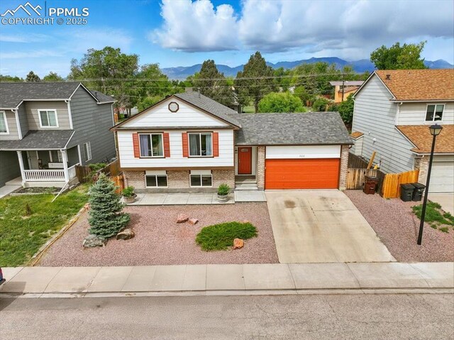 2032 Woodsong Way, Fountain, CO 80817 - split level home featuring brick siding, a mountain view, concrete driveway, and a garage