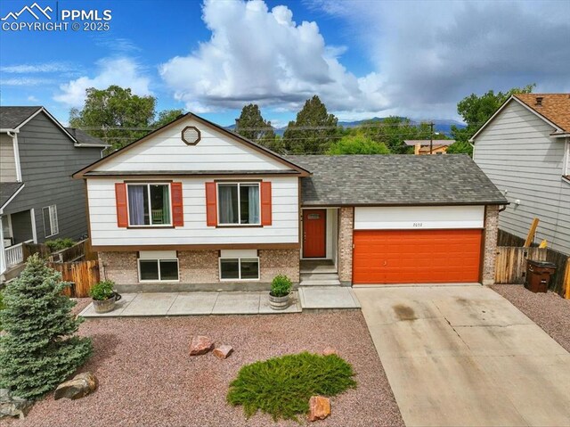 2032 Woodsong Way, Fountain, CO 80817 - split level home with brick siding, an attached garage, driveway, and roof with shingles