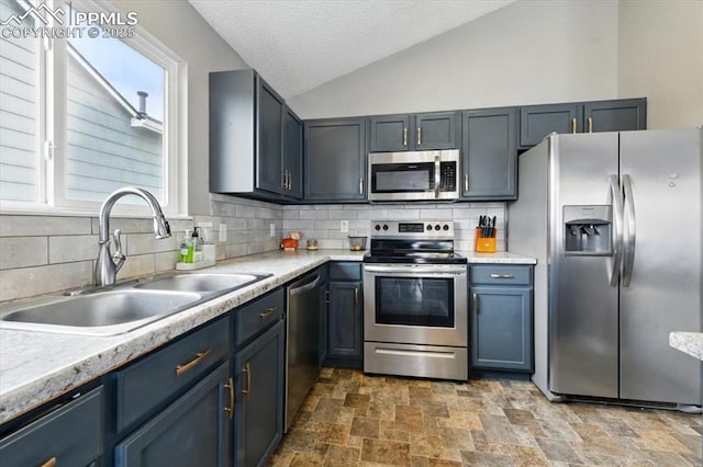 2032 Woodsong Way, Fountain, CO 80817 - kitchen with appliances with stainless steel finishes, a sink, stone finish floors, tasteful backsplash, and lofted ceiling