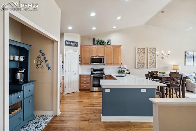 8492 Artesian Springs Pt, Colorado Springs, CO 80920 - kitchen featuring appliances with stainless steel finishes, a peninsula, a chandelier, light wood-style floors, and vaulted ceiling