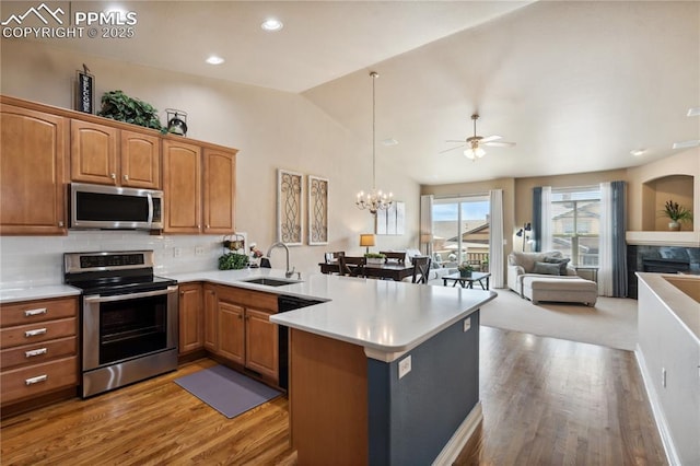 8492 Artesian Springs Pt, Colorado Springs, CO 80920 - kitchen with stainless steel appliances, a sink, a peninsula, light wood-style flooring, and vaulted ceiling