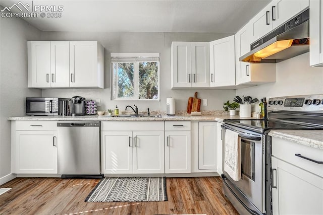 720 S Prospect St, Colorado Springs, CO 80903 - kitchen with wood finished floors, stainless steel appliances, under cabinet range hood, a sink, and white cabinetry