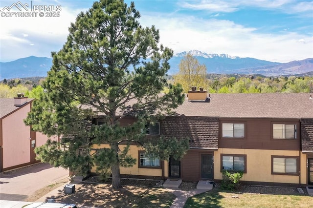 view of front of property with a mountain view, a shingled roof, and a chimney