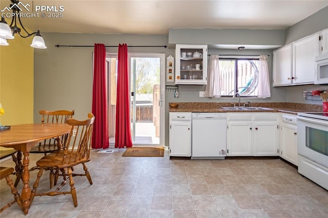 kitchen with white appliances, a sink, dark countertops, white cabinetry, and glass insert cabinets