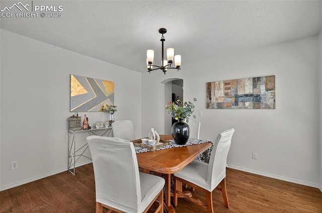 9025 Rochester Dr, Colorado Springs, CO 80920 - dining room featuring arched walkways, wood finished floors, baseboards, and a chandelier