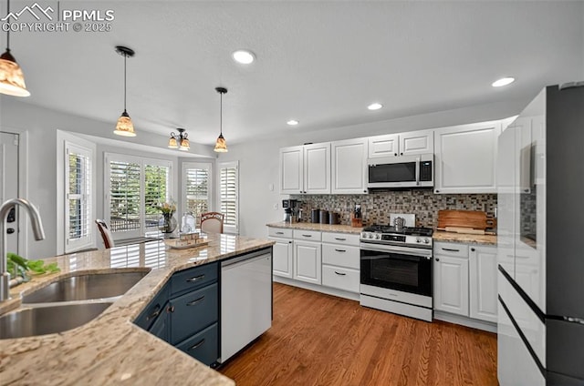 9025 Rochester Dr, Colorado Springs, CO 80920 - kitchen with appliances with stainless steel finishes, a sink, white cabinets, hanging light fixtures, and backsplash