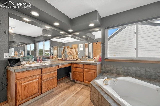 9025 Rochester Dr, Colorado Springs, CO 80920 - bathroom featuring a bath, double vanity, recessed lighting, wood finished floors, and plenty of natural light