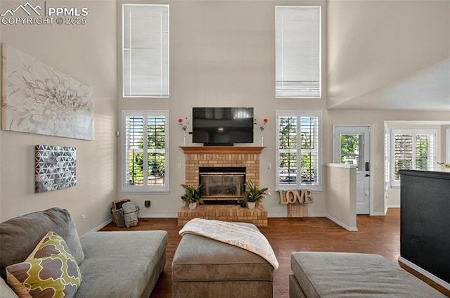 9025 Rochester Dr, Colorado Springs, CO 80920 - living room with a towering ceiling, wood finished floors, a brick fireplace, and baseboards