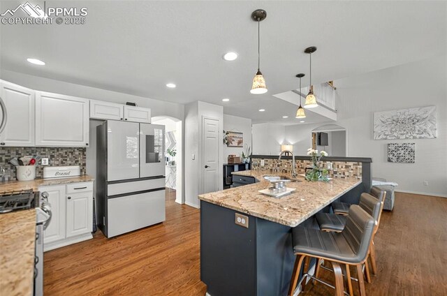 9025 Rochester Dr, Colorado Springs, CO 80920 - kitchen featuring smart refrigerator, stainless steel gas stove, arched walkways, wood finished floors, and a sink