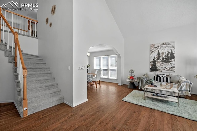 9025 Rochester Dr, Colorado Springs, CO 80920 - living room with arched walkways, high vaulted ceiling, stairway, wood finished floors, and baseboards