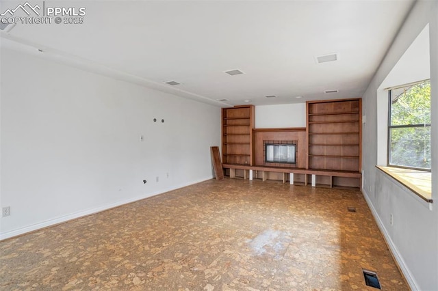 unfurnished living room with baseboards, visible vents, and built in features