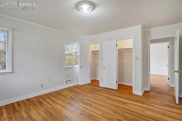 unfurnished bedroom with baseboards, visible vents, multiple windows, and light wood-type flooring