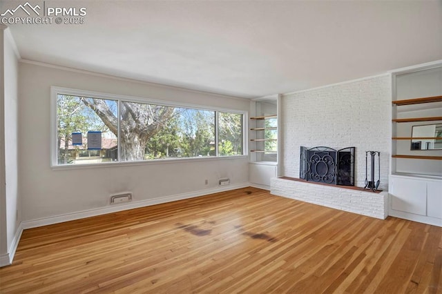 unfurnished living room with light wood-style flooring, a brick fireplace, and a wealth of natural light