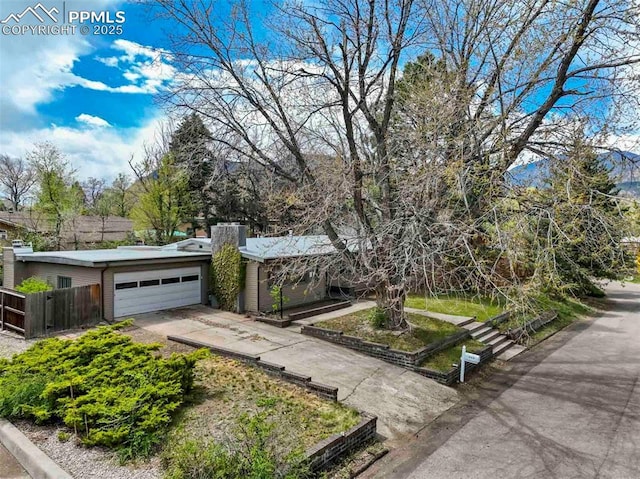 view of front of property with an attached garage, fence, and concrete driveway